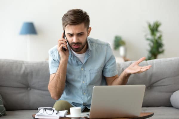 Angry man talking on phone disputing over computer laptop problem