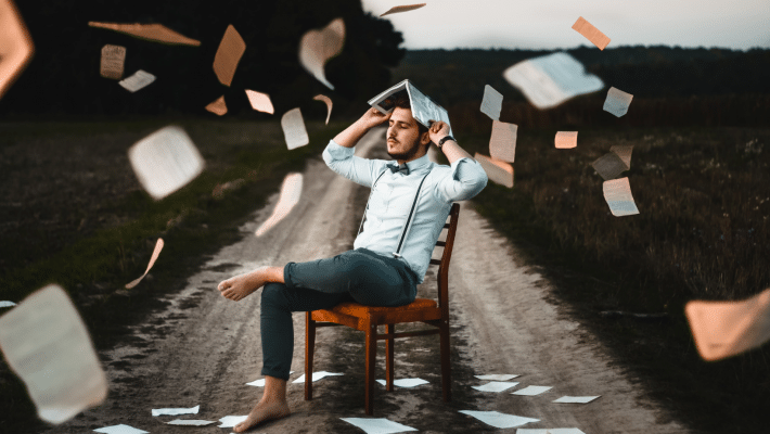 Homme assis avec des feuilles de livres qui tourbillonnent